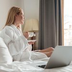 Sieviete viesnīcas halātā ar kafijas krūzi viesnīcas numurā